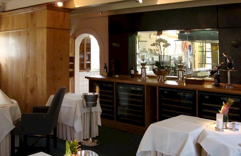 Wijnkoelerkast van eikenhout, met een glazen wand er bovenop tussen de restaurant en de keuken.